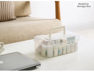 Close-up of clear plastic medicine storage box with white handle and organized pill bottles