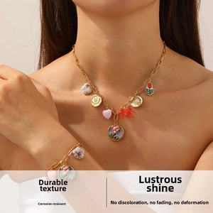 Close-up of gold chain necklace and bracelet with vintage enamel flower and heart charms