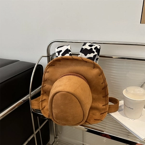 Unique brown suede cowboy hat shaped backpack with stylish black and white cow print straps