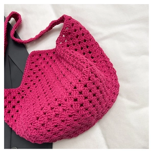 Dettaglio della borsa a tracolla intrecciata a mano fucsia su tessuto bianco