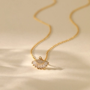 18K gold plated necklace with a fan-shaped zircon pendant on a beige textured background