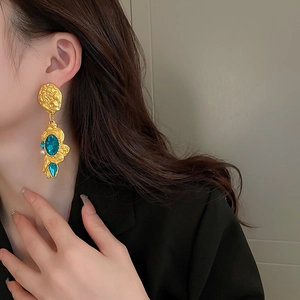 Vintage gold-toned flower earrings with blue gems and pearl on a fashion model