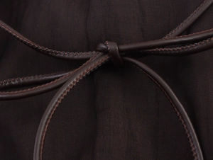 Detail of a dark brown chiffon dress featuring a thin leather drawstring waist tie