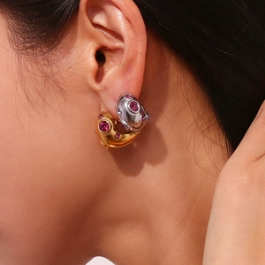 Macro view of bi-color earrings with pink gemstones on a model wearing them