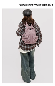 Detailed back view of pink-purple nylon backpack with functional pockets on a model