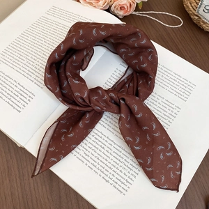 Detailed close-up of a brown paisley silk scarf necklace laid on vintage art books