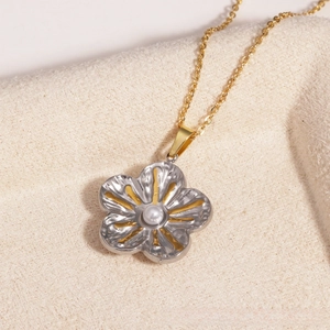 Vue détaillée d'un pendentif fleur bicolore avec une perle sur une chaîne dorée