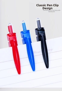 Detail of red, blue, and black retractable pen clips on a white notebook edge