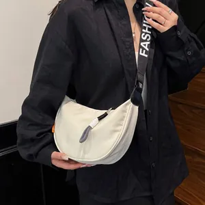 Close-up of a white crescent saddle bag with a wide strap featuring FASHION text