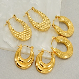 Three pairs of vintage gold U-shaped and textured thick hoop earrings on marble