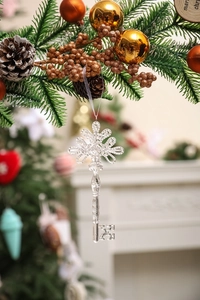 Close-up of a clear acrylic key-shaped ornament hanging on a festive Christmas tree branch