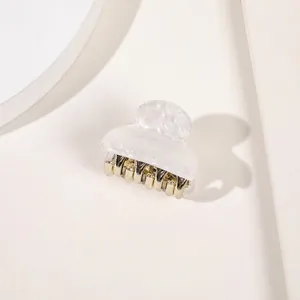 Detail of white marble texture acrylic hair claw clip with golden metal teeth
