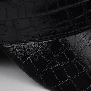 Gros plan macro montrant la texture crocodile brillante sur le chapeau en cuir PU noir