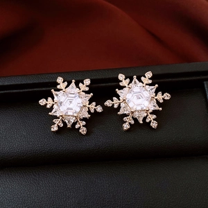 Macro shot of gold-plated snowflake stud earrings with sparkling cubic zirconia inlay