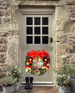 Close-up of Christmas wreath with red bow, gold bells and Merry Christmas sign on door