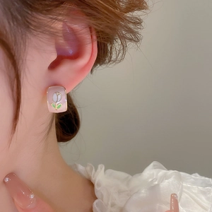 Close-up of elegant gold-plated tulip flower square earrings worn by a model