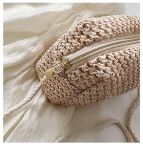 Detailed close-up of smooth metal zipper and dense woven texture on straw crossbody bag