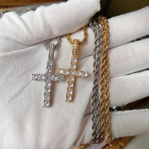Detailed view of gold and silver zircon cross pendants held in a white gloved hand