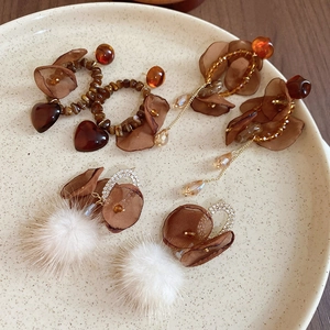 Close-up of retro fur pompom and mesh flower earrings with rhinestones on ceramic plate