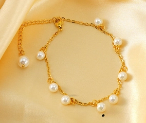 Detail of 18K gold-plated stainless steel anklet with pearls on luxury silk fabric