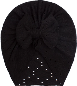Detail of black mesh baby turban featuring a large bow and elegant white pearl accents