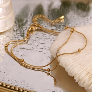 Macro shot of 18K gold plated double layer beaded snake chain on white coral stone