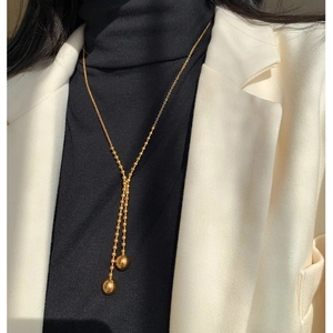 Elegant gold Y-shaped titanium steel necklace with ball pendants on a model