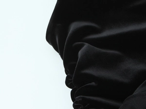 Détail rapproché de la texture du velours noir froncé sur une robe de soirée