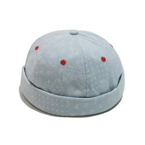 Close-up of light blue paisley print miki hat with red embroidered eyelets on canvas