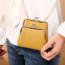 Detail of yellow kiss-lock bag featuring a pearl and metal chain shoulder strap