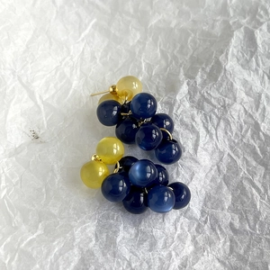 Details von Perlenohrringen mit blauen und gelben Harzperlen auf weißem Papierhintergrund