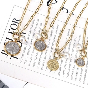 Detailed macro view of gold-tone chains with religious coin pendants and white pearls