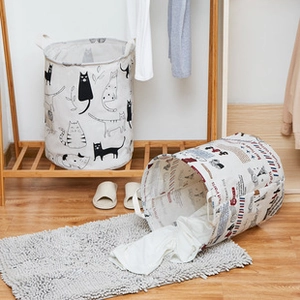 Collapsible laundry baskets with cat and city prints on a wooden shelf in a warm room