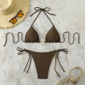 Detail of dark brown triangle bikini top with gold heart buckle on marble background