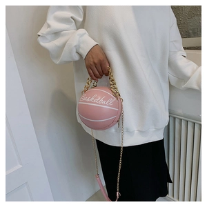 Detailed shot of pink basketball shaped crossbody bag with gold chain strap on model