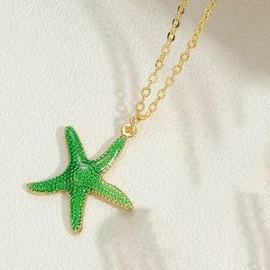 Detailed macro view of 14k gold starfish pendant with green enamel on a cable chain