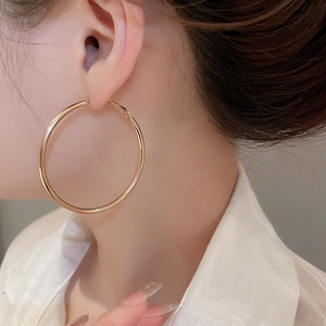 Close-up of large gold hoop earrings on model showing minimalist polished design