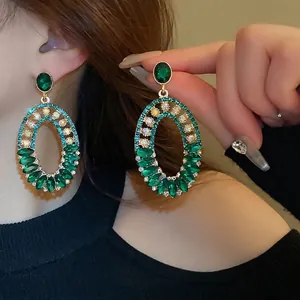 Elegant gold-tone oval drop earrings with emerald green stones and sparkling rhinestones