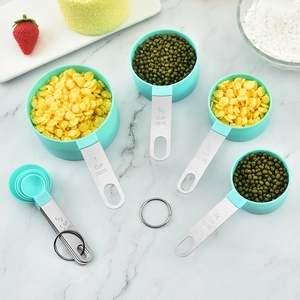 Stainless steel and teal measuring spoons and cups set on a marble surface background