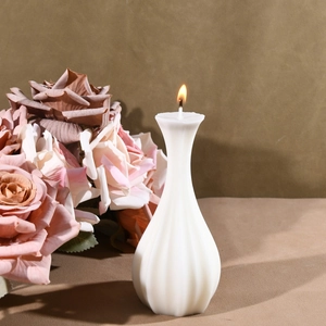 Close-up of burning striped white candle vase with elegant vertical textured details