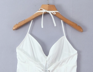 Detalle de blusa blanca de cuello halter con acabado satinado y cierre de lazo
