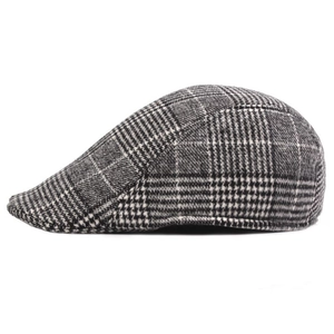 Detail of grey plaid flat cap showing intricate prince of wales check texture on the side