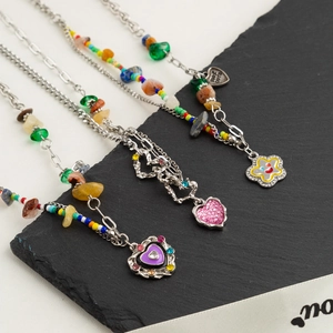 Colorful beaded necklaces with heart pendants and stones on natural rock background