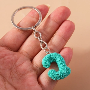 Detailed close-up of mint green letter C keychain with floral rose texture on metal ring
