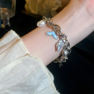 Close-up of ocean-themed silver chain bracelet with pearl, fish tail, and shell charms