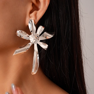 Close-up of model wearing oversized silver flower earrings with metallic petals