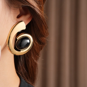 Detail of vintage gold spiral earring with black oval stone worn on model ear