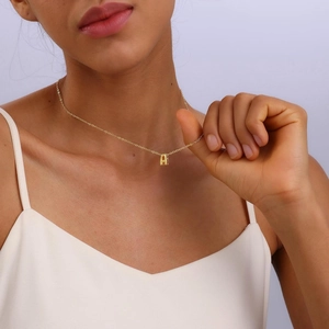 Macro shot of gold plated bubble letter A necklace on model showcasing shiny metal texture