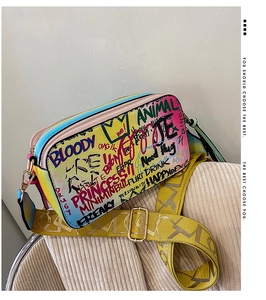 Detail of colorful graffiti crossbody camera bag with wide jacquard strap and gold hardware