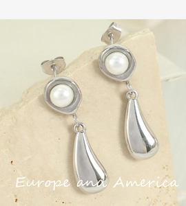 Macro detail of silver pearl drop earring featuring a polished metallic teardrop pendant